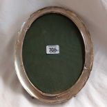 A LARGE OVAL CHINESE SILVER FRAMED PHOTO FRAME ON EASEL SHAPED BACK