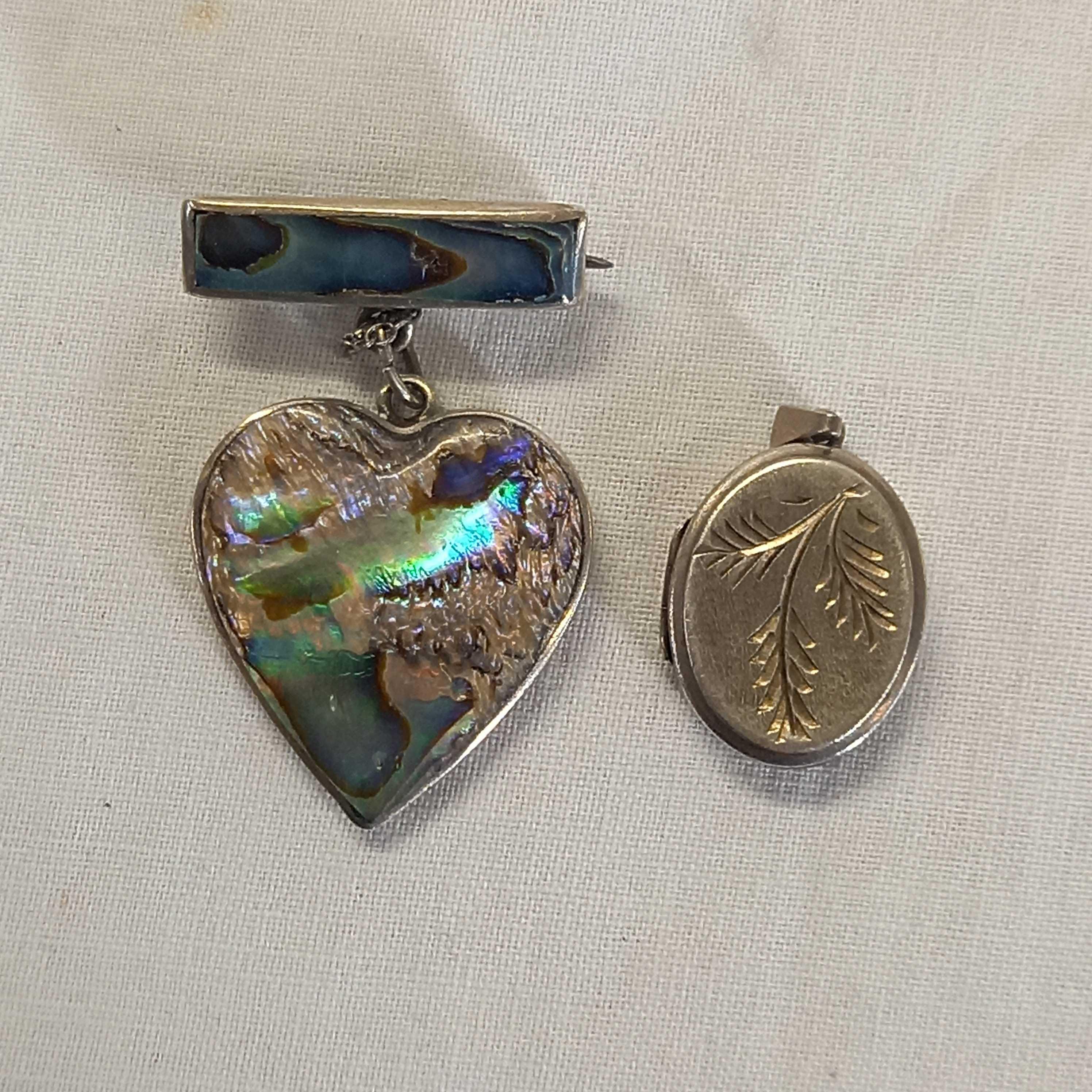 AN OVAL SILVER HINGED LOCKET & A SILVER HEART SHAPED FOB