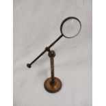 A VICTORIAN MAGNIFIER ON ADJUSTABLE BRASS STAND