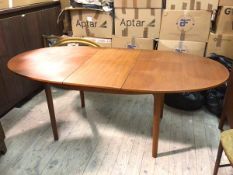 A mid century teak dining table, the tablet shaped top with magic leaf extension, on straight turned