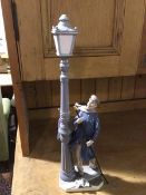 A Spanish Lladro style porcelain figure, The Lamplighter, complete with pole, decorated with