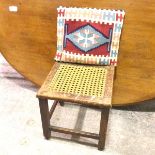 A 1920s oak stool with cane seat on straight supports united by box stretchers and a later kelim