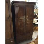 A late 19thc mahogany wardrobe, the moulded cornice above two panel doors enclosing a hanging rail