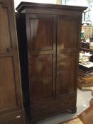 A late 19thc mahogany wardrobe, the moulded cornice above two panel doors enclosing a hanging rail