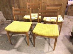 A set of four mid century teak side chairs, each with two rail backs above upholstered seats, on