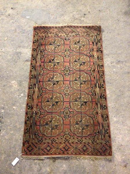 A Turkoman rug with two rows of five elephant feet medallions, red field within a geometric