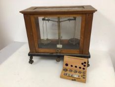An Edwardian set of scales in glass case and adjustable base together with a set of weights