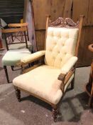 A late 19thc/early 20thc armchair, with moulded crest above a button back and upholstered arms and