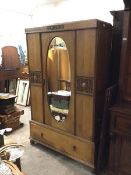 An Edwardian oak wardrobe, the moulded cornice above a single mirrored door, with hanging rail and