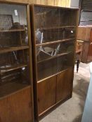 A mid century teak tall wall unit, fitted sliding glass doors enclosing interior fitted four