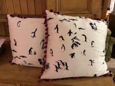 A pair of cushions, covers with penguins on ivory field with maroon pompom piping to edges, internal