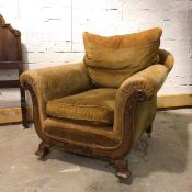 A late 19thc/early 20thc armchair, with cushion back and seat, flanked by scrolled arms, with