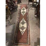 A North West Persian runner, with two geometric diamond medallions, ivory field, on repeating scaled