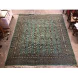 A Turkoman green rug, the central field with seven rows of guls, separated by stylised diamonds,