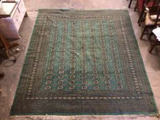 A Turkoman green rug, the central field with seven rows of guls, separated by stylised diamonds,