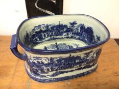 A blue and white Victorian style foot bath depicting a Southern European Street scene, handles to