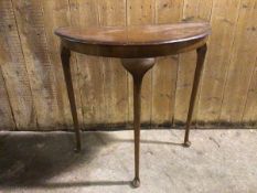 A 1930s/40s mahogany demi lune table, with cabriole legs ending in pad feet (73cm x 75cm x 38cm)