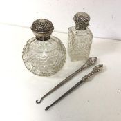 Two Edwardian Birmingham silver handled button hooks, two cut glass bottles with silver tops (4)