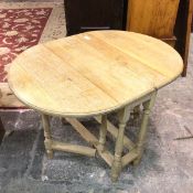 An oval bleached oak drop leaf gateleg table raised on turned baluster supports (closed: 71cm x 75cm