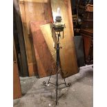 A converted adjustable brass oil lamp on wrought iron tripod base, with copper tap allowing for