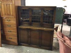 A 1920s two part oak bookcase, the upper tier with three glazed doors, with shelved interior, the