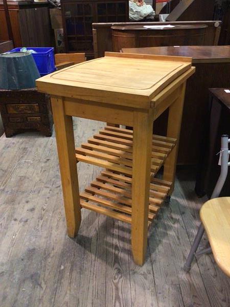 A modern beech butcher's block with cutting board above two slatted tiers, on straight square