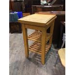 A modern beech butcher's block with cutting board above two slatted tiers, on straight square