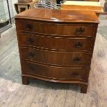 A reproduction serpentine fronted mahogany chest of drawers fitted four graduated drawers, on