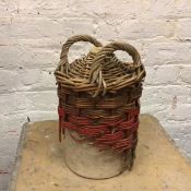 A stoneware jug within a wicker carrying case, some losses to wicker, with handles to sides (35cm