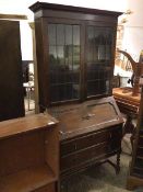A 1920s oak bureau bookcase, the moulded cornice above two glazed doors, adjustable shelves and