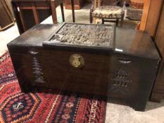 A Chinese camphorwood chest, the slightly angled top with intricately carved panel depicting a