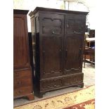 A late 19thc/early 20thc oak Tudor style wardrobe with a pair of panelled doors enclosing hanging