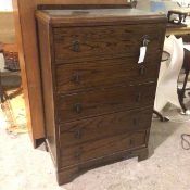 A 1920s/30s oak and elm chest of drawers, with ledge back and moulded edge top above five drawers,