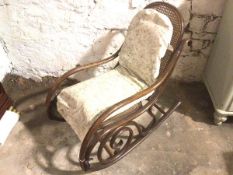 An early 20thc rocking chair, with bentwood frame and cane back and seat, with later cushions (