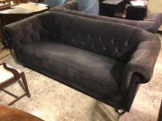 A contemporary three seater sofa with button back and scrolled button arms, in a navy blue