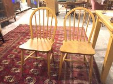 A pair of Ercol light ash spindle back kitchen chairs, with shaped saddle seats, on turned