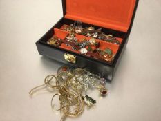 A jewellery box containing a collection of yellow metal and gilt metal chains, paste set floral
