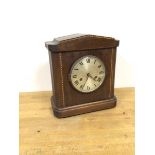 An Edwardian mahogany mantel clock with arched pediment above a circular metal dial and roman