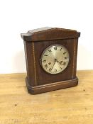 An Edwardian mahogany mantel clock with arched pediment above a circular metal dial and roman