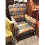 A 1920s/30s armchair in a later plaid upholstery, on straight tapering supports ending in castors (