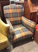 A 1920s/30s armchair in a later plaid upholstery, on straight tapering supports ending in castors (