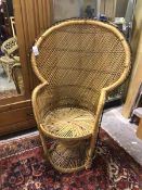 A woven cane peacock chair, the flared back with three stylised flowerheads over a circular seat and