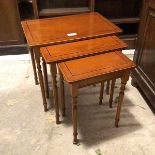 A set of three yew wood nesting tables, each with a rectangular top and moulded edge, on turned