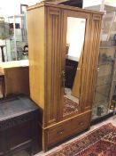 An Edwardian ash wardrobe, with central mirrored door enclosing an interior fitted hanging space,