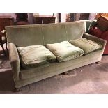 A large three seater Edwardian sofa, in an allover green upholstery, with three seat cushions, on