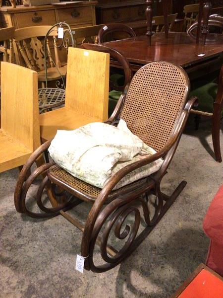 An early 20thc rocking chair with bentwood frame and cane back and seat, with later cushions (83cm x