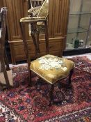 An Edwardian nursing chair, with padded and upholstered top rail above a pierced inlaid splat, and