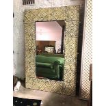 A large decorative wall or standing mirror, the rectangular glass within a painted sheet metal