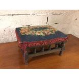 A 1920s footstool with grospoint top with fringed edge above a turned gallery, on turned supports (