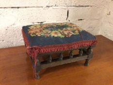 A 1920s footstool with grospoint top with fringed edge above a turned gallery, on turned supports (